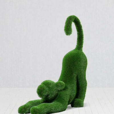 Cachorro de león estirándose de pasto artificial – Figura topiaria