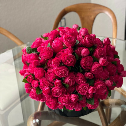 Rosas inglesas rosa intenso en jarrón de vidrio negro