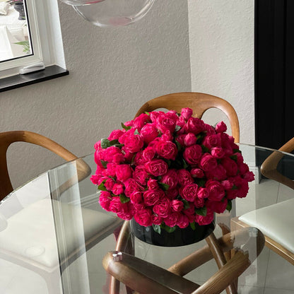 Rosas inglesas rosa intenso en jarrón de vidrio negro