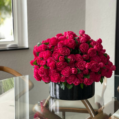 Rosas inglesas rosa intenso en jarrón de vidrio negro