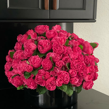 Rosas inglesas rosa intenso en jarrón de vidrio negro