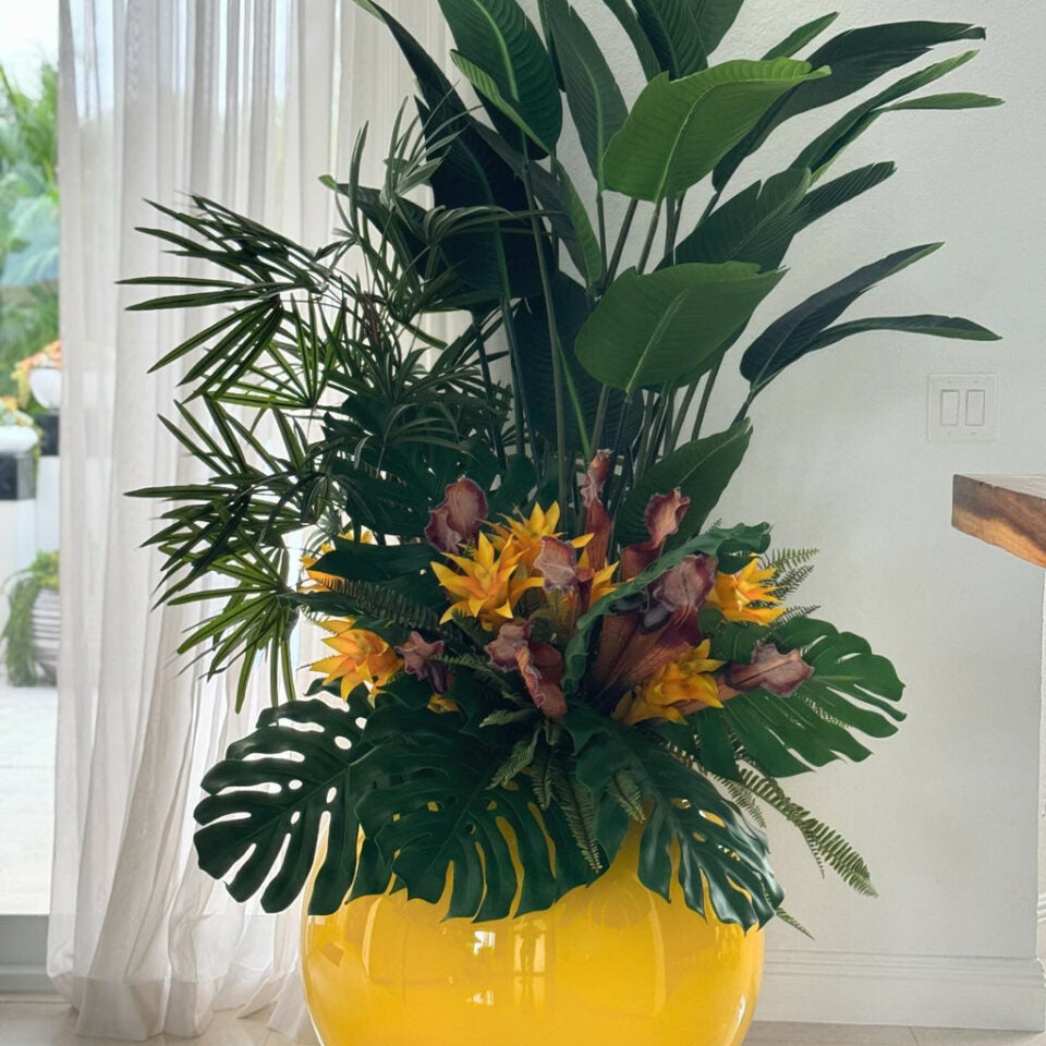 Arreglo de plantas tropicales en maceta esférica amarilla